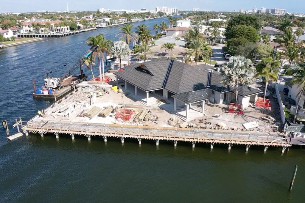 A luxurious waterfront home in Fort Lauderdale with a pool, palm trees, and a clear blue sky.