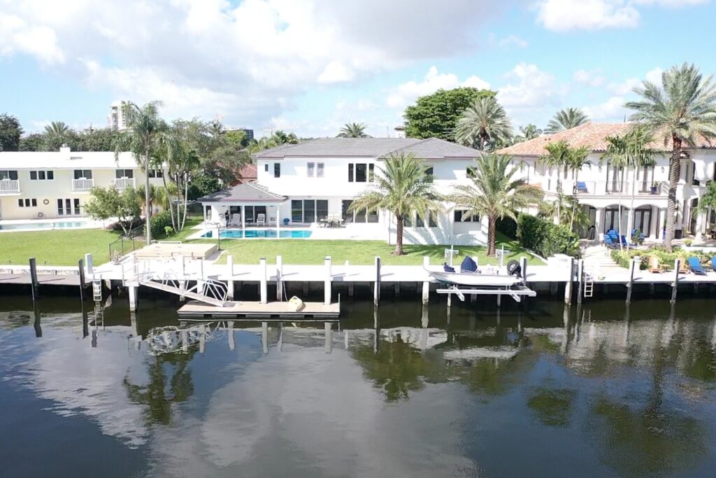 Exterior view of a modern waterfront home at 33 Isla Bahia Dr. 1, showcasing a sleek design and lush landscaping.