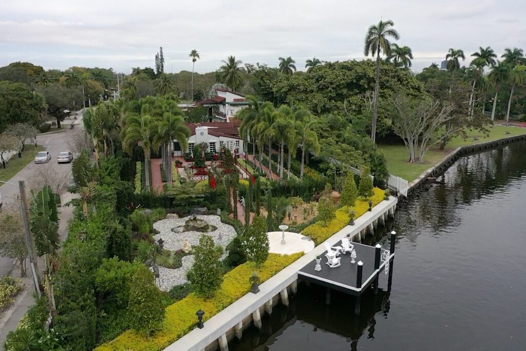 Exterior view of 416 Palm Ave showcasing modern architecture, lush landscaping, and a clear blue sky.