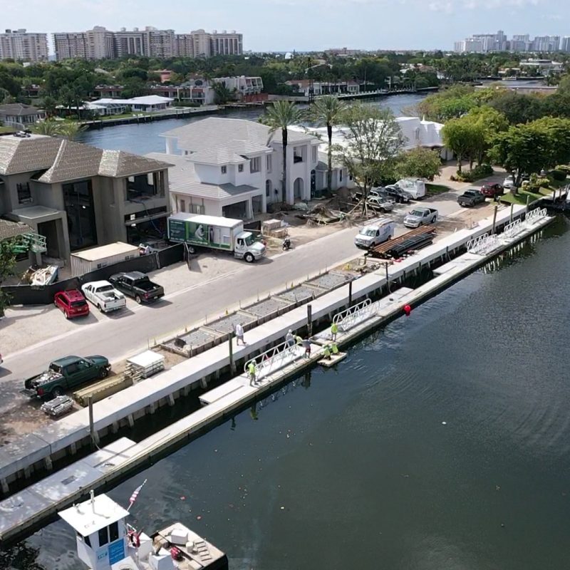 A modern barge with a sleek design docked at a waterfront, showcasing the 230 N. Compass Barge2.