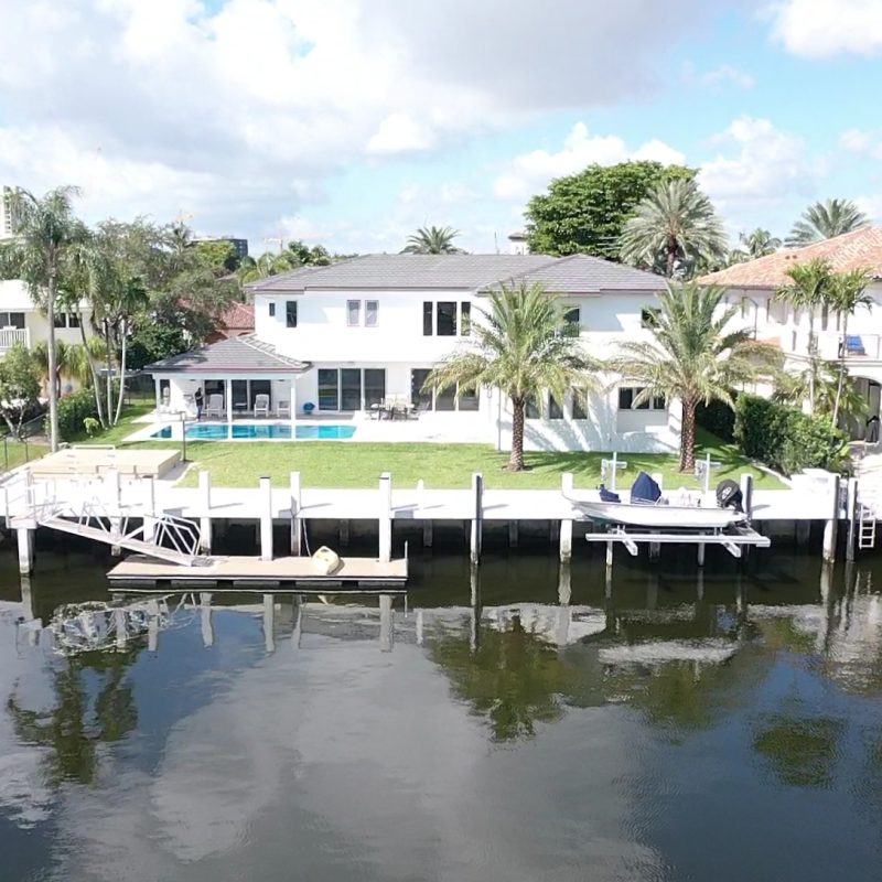 Exterior view of a modern waterfront home at 33 Isla Bahia Dr. 1, showcasing a sleek design and lush landscaping.