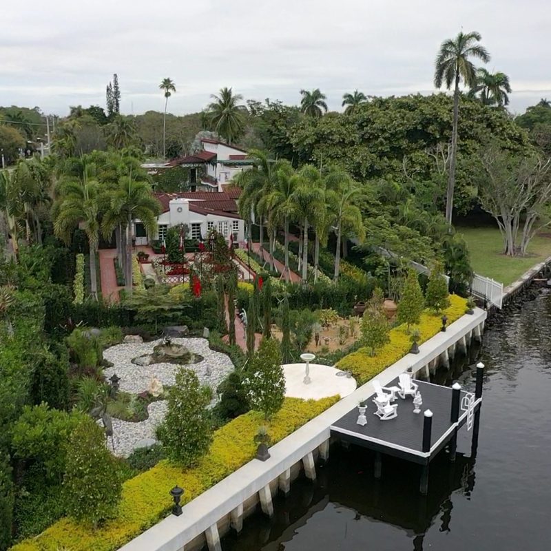 Exterior view of 416 Palm Ave showcasing modern architecture, lush landscaping, and a clear blue sky.